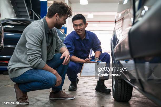 car mechanic checking wheel in garage - mechanic client stock pictures, royalty-free photos & images