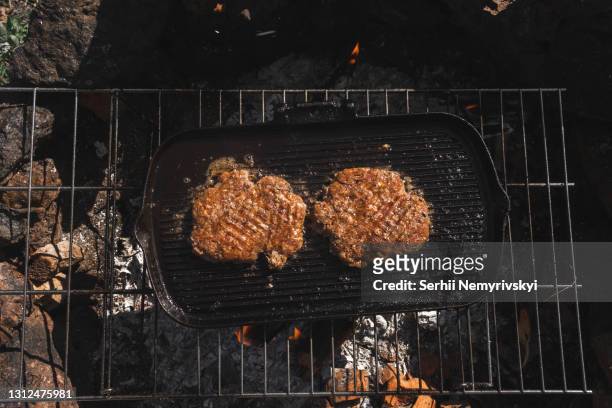 beef milled meat on hamburger, tourist grid. cast-iron pan grill with flames. delicious food during vacation, camping. top down view - camping with bone fire stock pictures, royalty-free photos & images