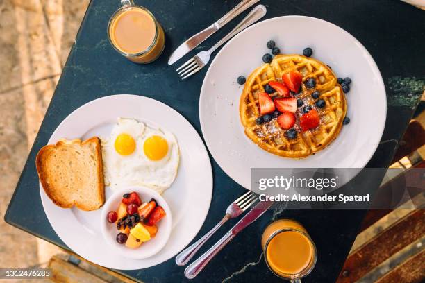 breakfast with sunny side up fried eggs, waffle and fruits - setzei stock-fotos und bilder