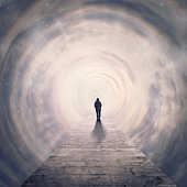 woman walking foreward in tunnel of clouds to the light