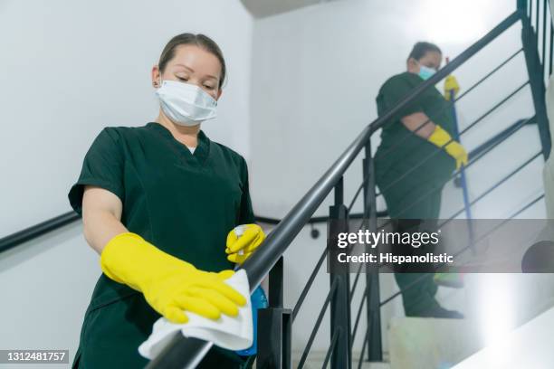 cleaners cleaning the handrail of the stairs at a building during the pandemic - empregado-da-limpeza imagens e fotografias de stock
