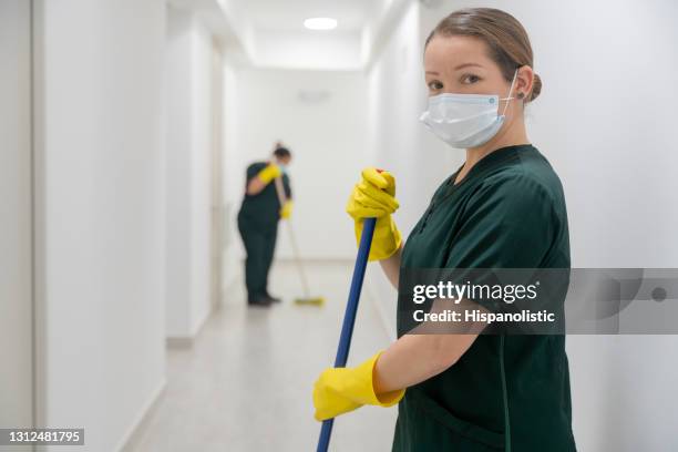 reiniger trägt eine gesichtsmaske bei der arbeit in einem bürogebäude, das die böden fegt - cleaner man uniform stock-fotos und bilder