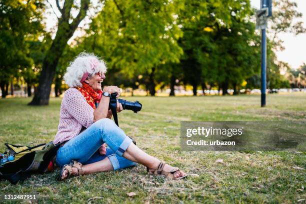 senior tourist woman photographing in park - senior photographer stock pictures, royalty-free photos & images