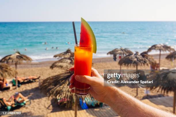 man drinking watermelon cocktail at the beach, personal perspective (pov) point of view - cold drink beach stock pictures, royalty-free photos & images