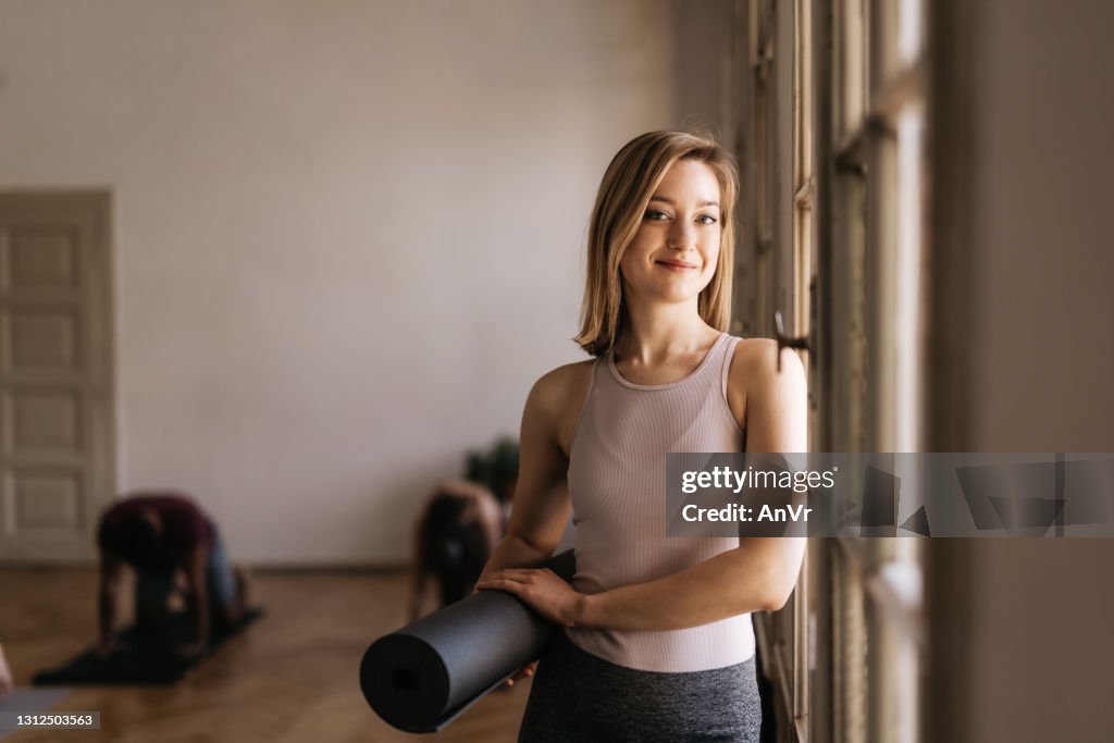 Bella giovane donna in possesso di un tappetino da yoga