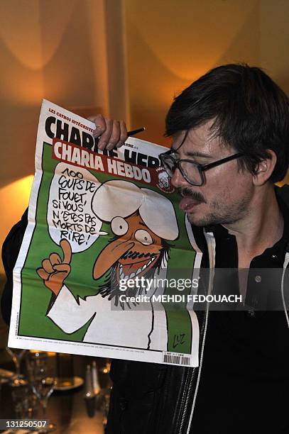 The Charlie Hebdo' s cartoonist Luz sticks out his tongue as he shows a special edition of French satirical magazine Charlie Hebdo, on November 3,...