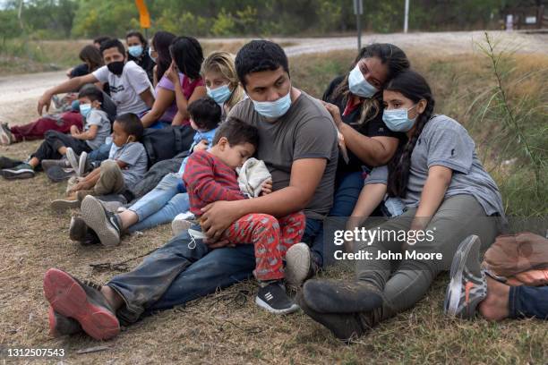 Guatemalan family waits with fellow immigrants to board a U.S. Customs and Border Protection bus to a processing center after crossing the border...