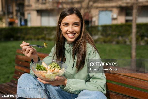 attractive caucasian woman eating her lunch in park - lunch break stock pictures, royalty-free photos & images