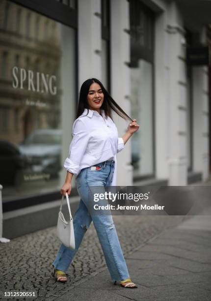 Saint Linh wearing white Prada Cleo bag, white Tommy Hilfiger blouse and blue destroyed jeans and Jimmy Choo heels on April 11, 2021 in Berlin,...