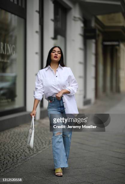 Saint Linh wearing white Prada Cleo bag, white Tommy Hilfiger blouse and blue destroyed jeans and Jimmy Choo heels on April 11, 2021 in Berlin,...