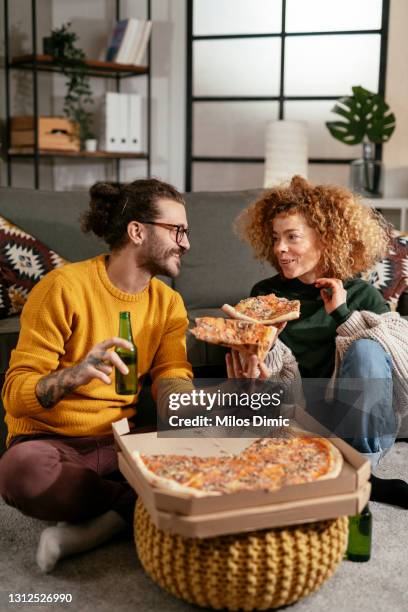 happy couple drinking beer and eating pizza, spending time together at home stock photo - couple eating stock pictures, royalty-free photos & images