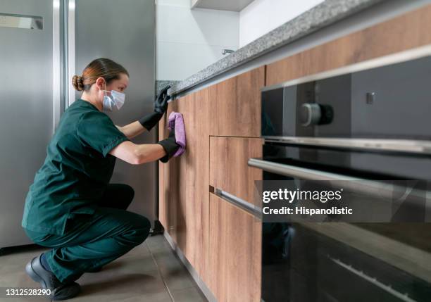 latin american cleaner wearing a facemask while cleaning the kitchen - criada imagens e fotografias de stock