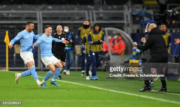Phil Foden of Manchester City runs towards Pep Guardiola, Manager of Manchester City as he celebrates with team mate Kyle Walker after scoring their...