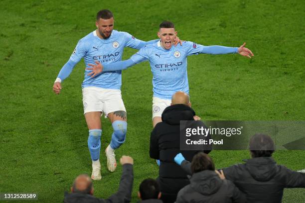 Phil Foden of Manchester City runs towards Pep Guardiola, Manager of Manchester City as he celebrates with team mate Kyle Walker after scoring their...