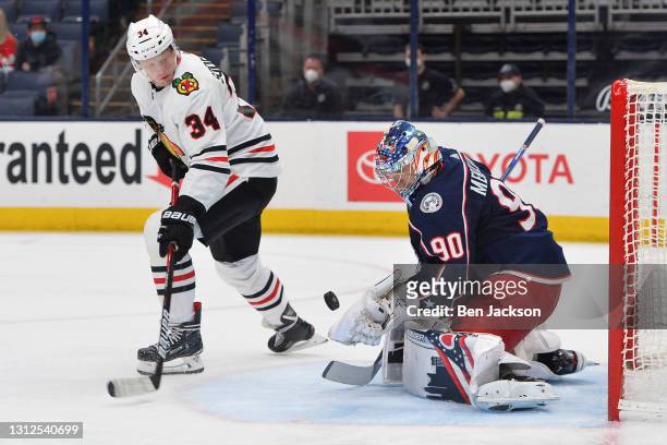 Goaltender Elvis Merzlikins of the Columbus Blue Jackets and Carl Soderberg of the Chicago Blackhawks follow the puck during the third period of a...