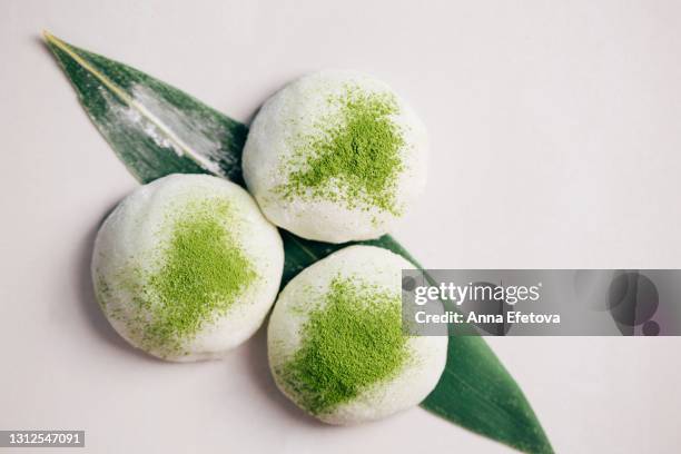 three mochi desserts with matcha tea powder on concrete textured background. traditional japanese cake. flat lay style - mochi imagens e fotografias de stock