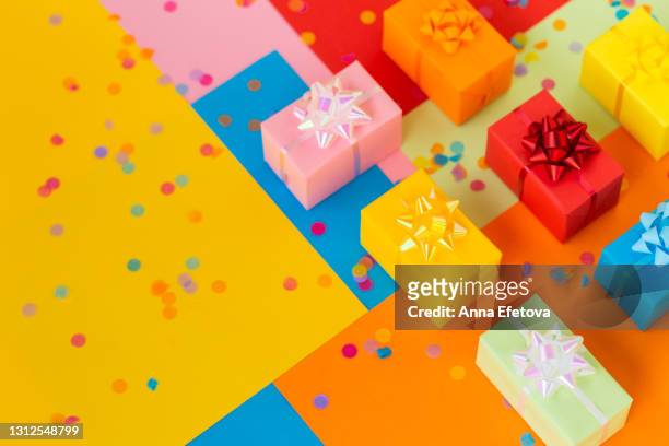 set of many multi colored gift boxes on colorful multi colored background with paper confetti. sustainable lifestyle and zero waste concept. top view and close-up - birthday gift stock-fotos und bilder