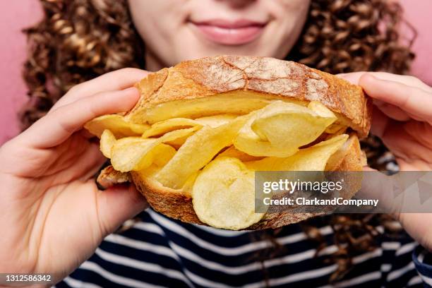 young woman holding a crisp sandwich - crisps stock pictures, royalty-free photos & images