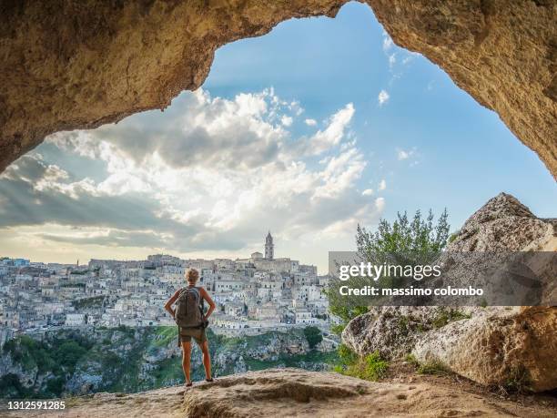 woman hiker looking city of matera from a cave on the hill - matera stockfoto's en -beelden