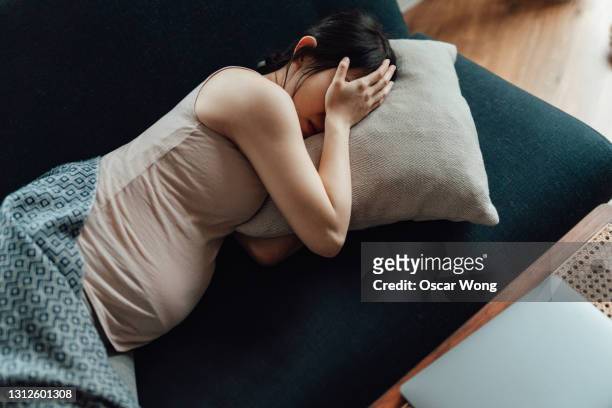 pregnant woman covering her eyes with hands while laying on sofa - pregnant bildbanksfoton och bilder