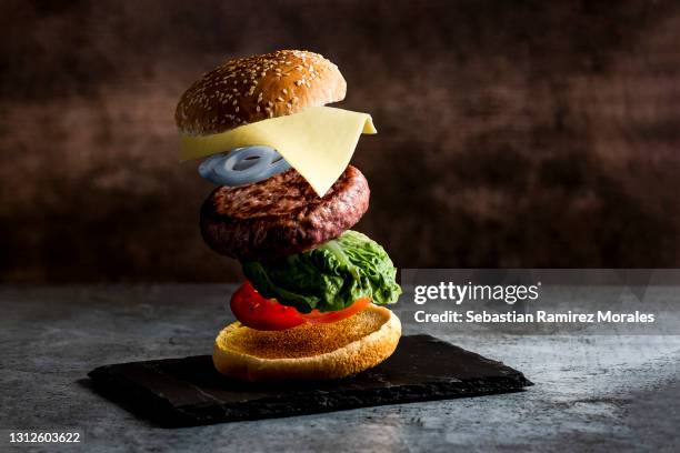 burger with separated floating ingredients on black background. - wallpaper roll stockfoto's en -beelden