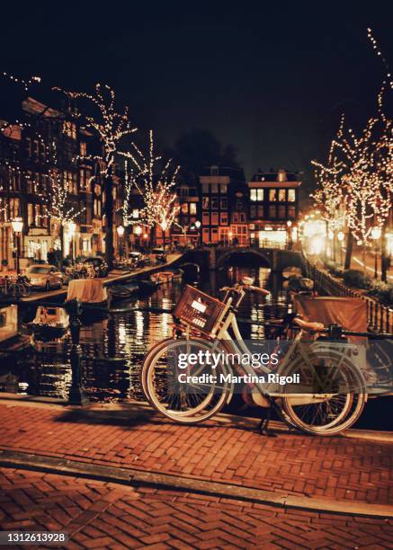 bicycles parked near amsterdam canal at night, christmas time - amsterdam winter stock pictures, royalty-free photos & images