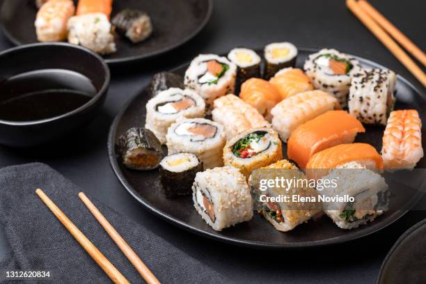 sushi lunch, rolls and sushi with salmon and shrimp with soy sauce on a black platter - sushi plate stock pictures, royalty-free photos & images