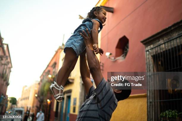 vader die dochter opheft in de lucht - humility stockfoto's en -beelden