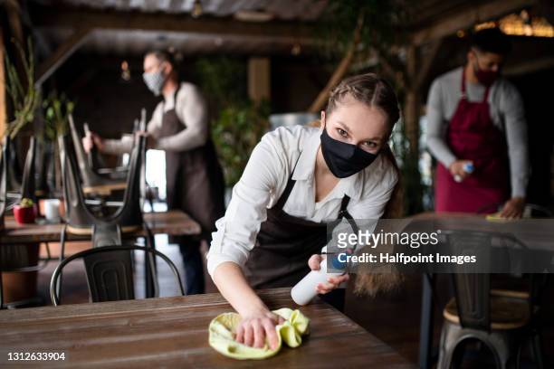 waitress disinfecting tables in restaurant, coronavirus and new normal concept. - opening event stock pictures, royalty-free photos & images