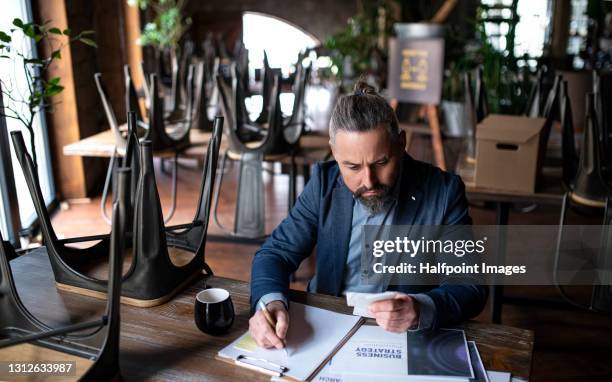 frustrated manager of restaurant working at table, coronavirus and end of business concept. - bankrupt restaurant stock pictures, royalty-free photos & images