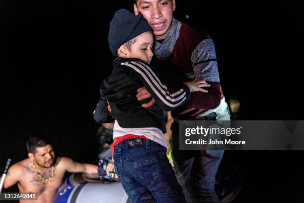 Teenage immigrant lifts a younger boy onto U.S. Soil after a human trafficker , smuggled them by dinghy across the the U.S.-Mexico border on April...