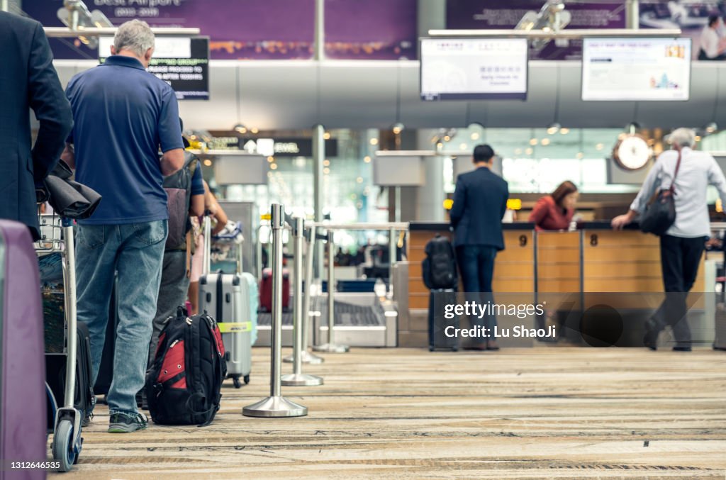 Passengers lined up at the airport to check in their luggage.