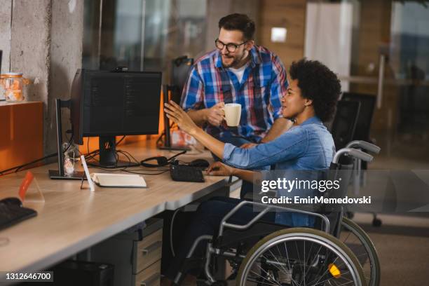 gehandicapte computerprogrammeur die in een rolstoel bij werkplaats zit en met een collega samenwerkt - disability working stockfoto's en -beelden