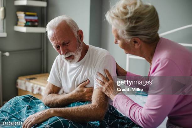 äldre man som lider av bröstsmärta i sängen - hjärtattack bildbanksfoton och bilder