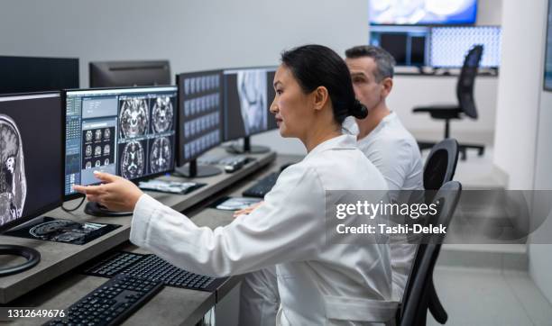 two radiologists looking at mri scan on computer - radiologist stock pictures, royalty-free photos & images