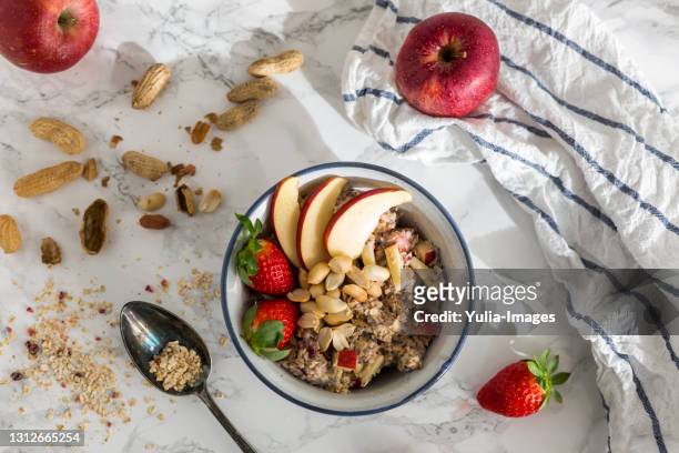 bowl of oats porridge topped with fruit and nuts - fibra fotografías e imágenes de stock