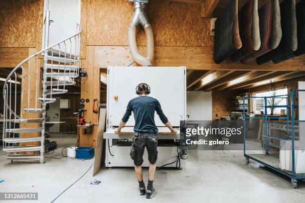 zimmermann zieht holzplatte durch bandschleifmaschine - carpentry tools stock-fotos und bilder