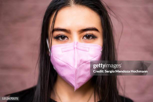 close up of young latino woman wearing a face mask and looking at the camera - n95 face mask - fotografias e filmes do acervo