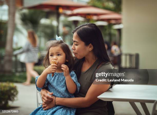 mom with toddler protecting her ice cream cone - filipino family eating fotografías e imágenes de stock