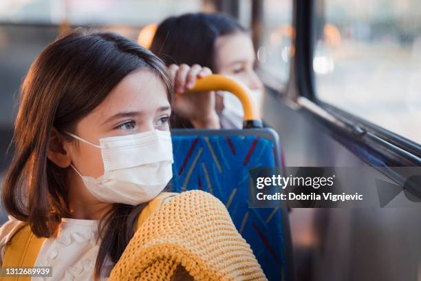 fröhliches mädchen sitzt in einem bus mit schutzmaske auf - girl driving stock-fotos und bilder