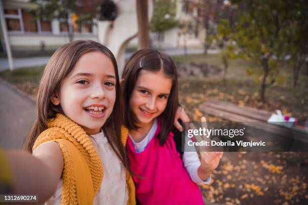 lächelnde kinder, die ein selfie machen - friedenszeichen handzeichen stock-fotos und bilder