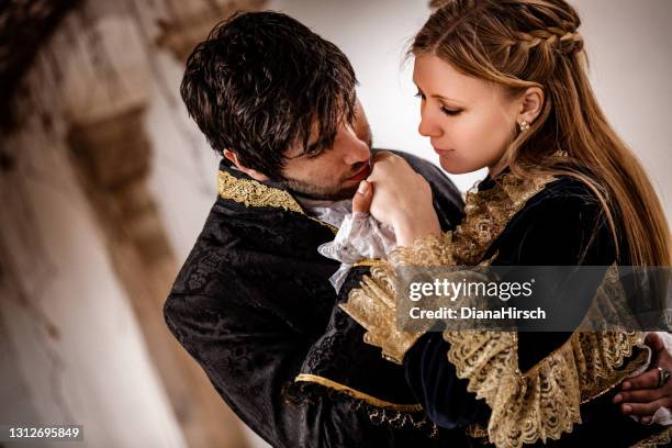 close up portrait of the handsome romeo kissing the beautiful juliets hand - princess stock pictures, royalty-free photos & images