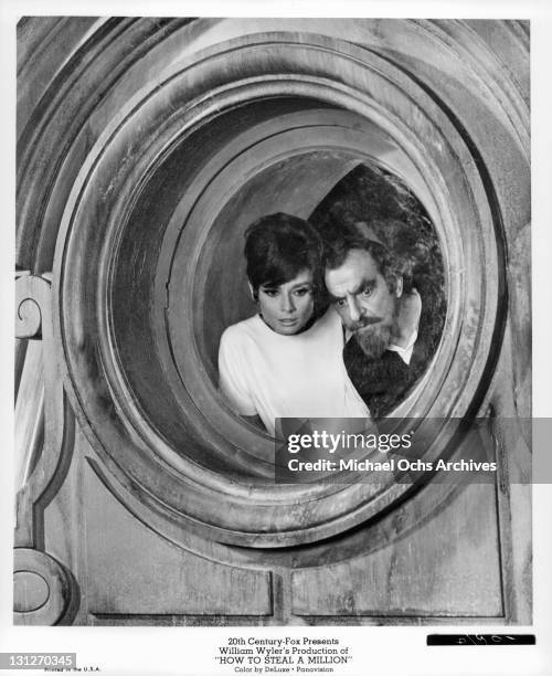 Audrey Hepburn and Hugh Griffith peer from an attic window in a scene from the film 'How To Steal A Million', 1966.