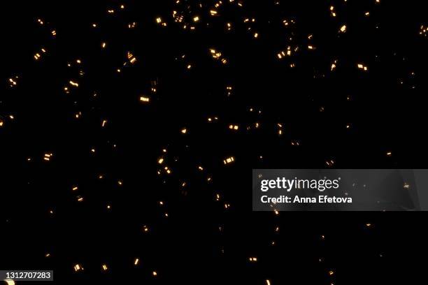 glittering golden confetti on black isolated background. christmas and new year concept in trendy festive golden color. - confetti gold ストックフォトと画像