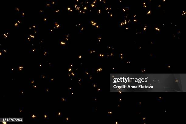 glittering golden confetti on black isolated background. christmas and new year concept in trendy festive golden color. - confete - fotografias e filmes do acervo