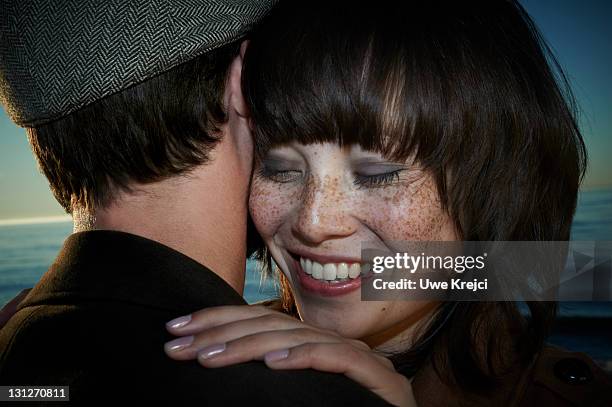 Young couple embracing on beach, smiling, close-up