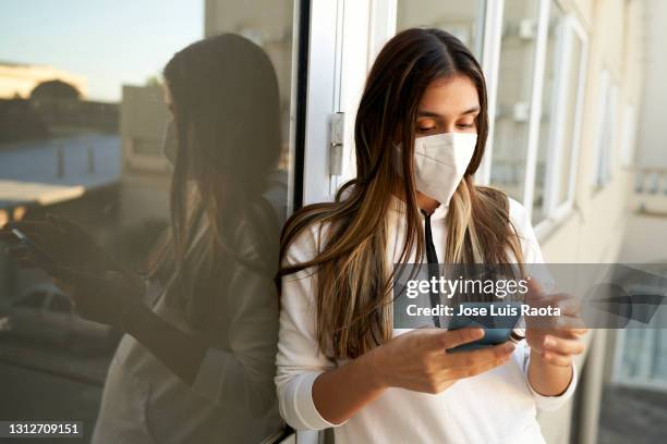 young latin woman looking at her phone - argentina covid stock pictures, royalty-free photos & images