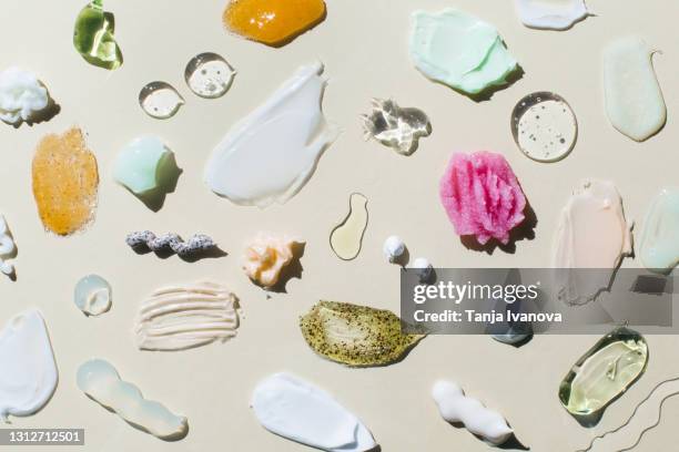 set textured multicolored smears cosmetic products on beige background. samples of creams, face gel, scrubs with exfoliating particles, serum. flat lay, top view. - skincare stockfoto's en -beelden