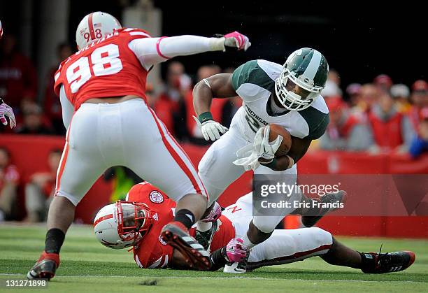 Running back Le'Veon Bell of the Michigan State Spartans kicks free from linebacker Lavonte David and tries to avoid defensive end Josh Williams of...