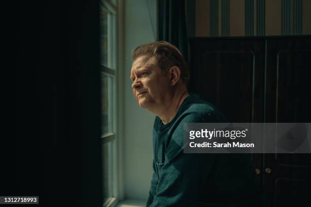 portrait of man looking out of window - nostalgie photos et images de collection